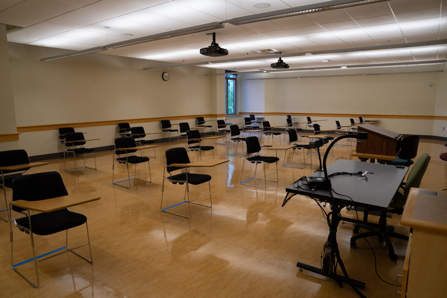 A college classroom with spaced out, empty desks.