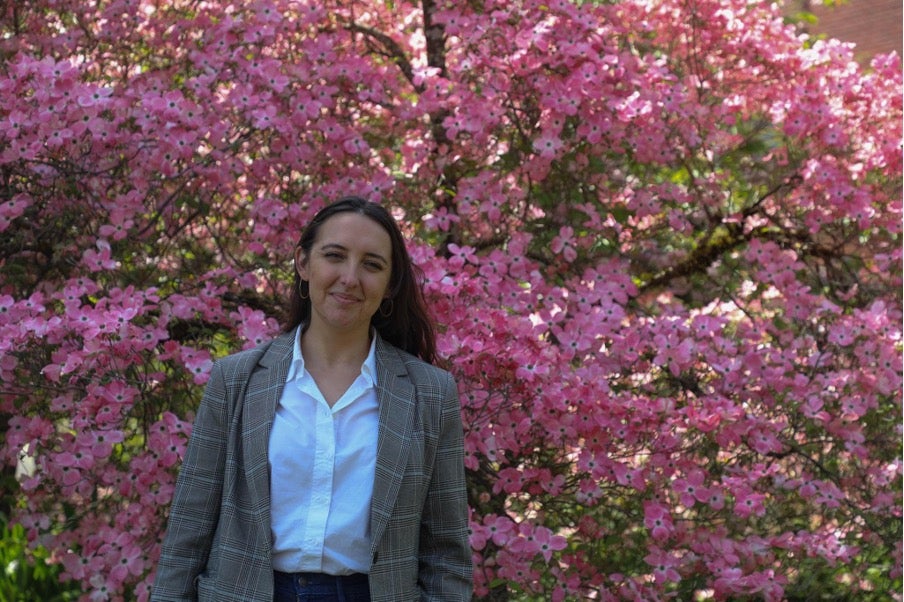 Gabriela Chitwood stands in front of a tree with pink flowers.