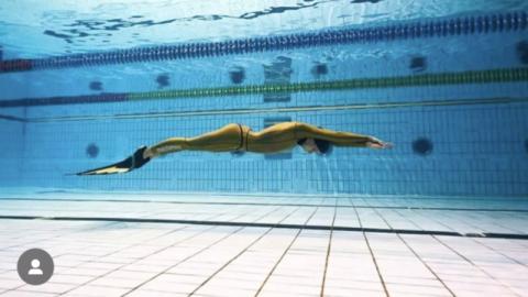 Diver swims under water of pool 