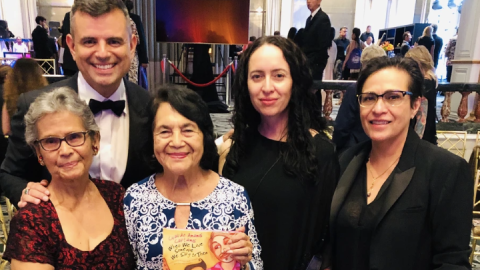 Ernesto Martínez standing next to Adelina Anthony and Dolores Huerta holding children’s book. 