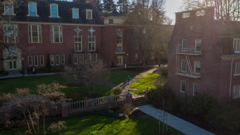 Students walking between red brick campus buildings on a sunny winter day..