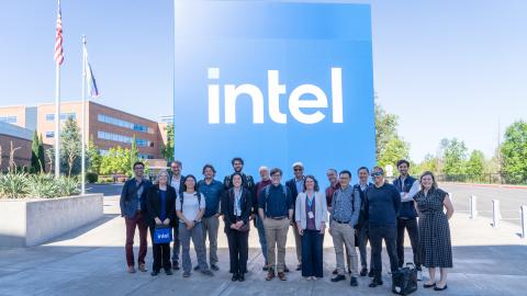 A group of people stand in front of a 15-foot tall blue Intel sign.