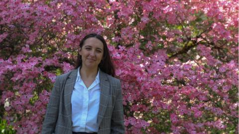Gabriela Chitwood stands in front of a tree with pink flowers.