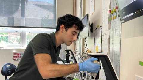 Lazar Isakharov uses a pipette to transfer material in a lab.