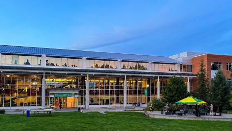 The UO Portland library building at dusk with lights on inside the building.