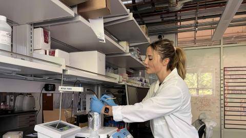 Tallula Wynia leans over a scale in a laboratory. 