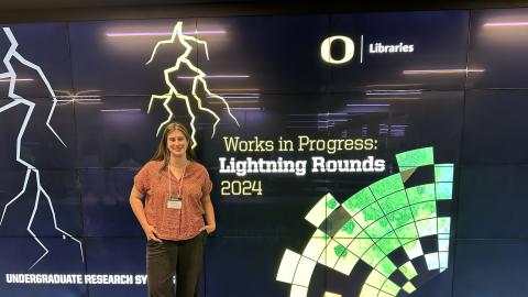 Tapley Sorenson stands in front of a sign at the 2024 Undergraduate Research Symposium.