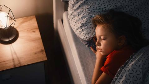 A young child sleeping in bed with their head on a pillow.