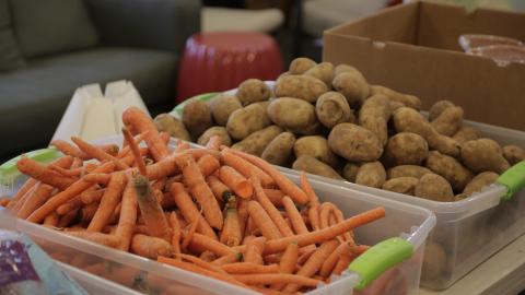 Bins of carrots and potatoes sit on a table.