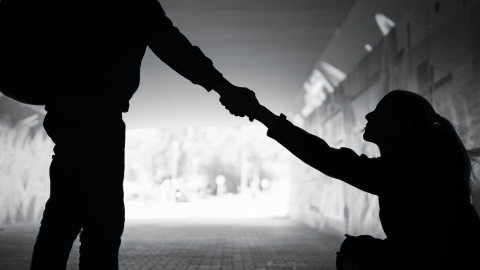 Silhouette of a person extending a hand to help someone up.