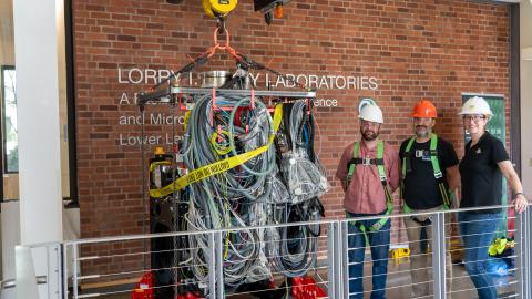 Staff pose with the S/TEM column as it is prepared to be craned down into the CAMCOR space.