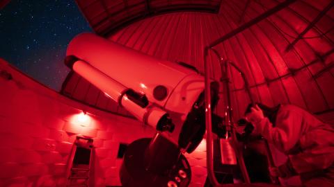A person looks through a telescope at the Pine Mountain Observatory.