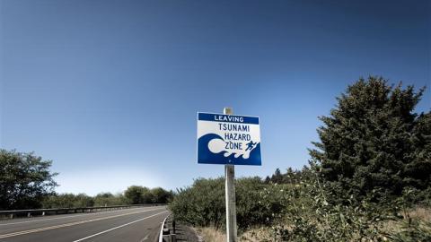 A sign on the side of a road indicating that it is a tsunami hazard zone.