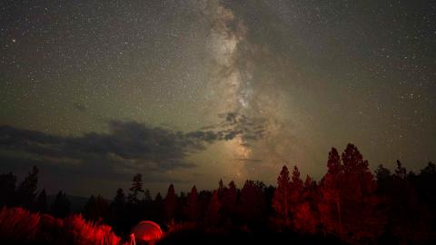 The Milky Way in the night sky above the red-lit dome of the Pine Mountain Observatory.