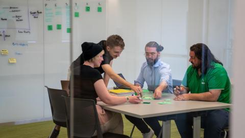 A group of graduate students collaborate around a table piled with sticky notes.