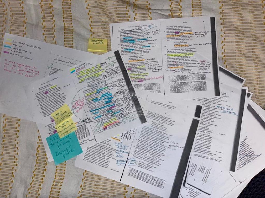 Printed pages of text show color-coded markups by a student performing text analysis.