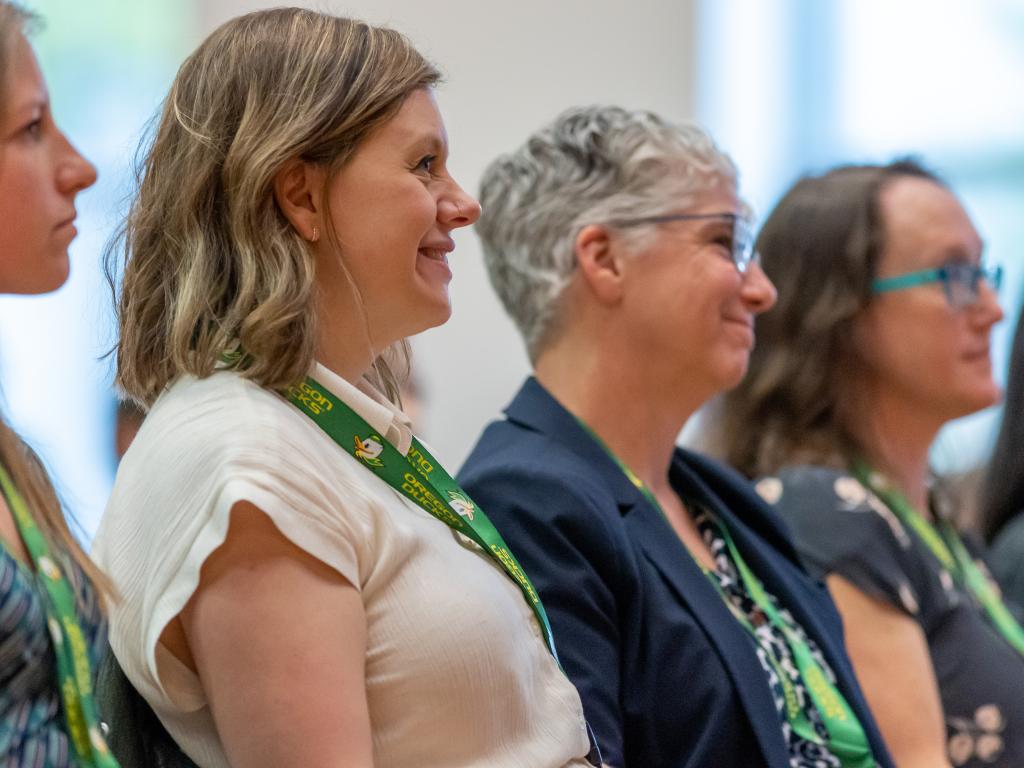 Four women seen from the side look in the same direction at a person speaking, who is not visible in the photo.