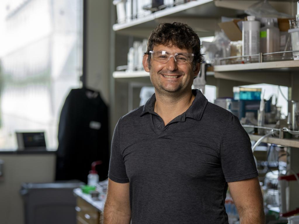 A portrait of Shannon Boettcher, a white man wearing lab glasses while standing in a lab.