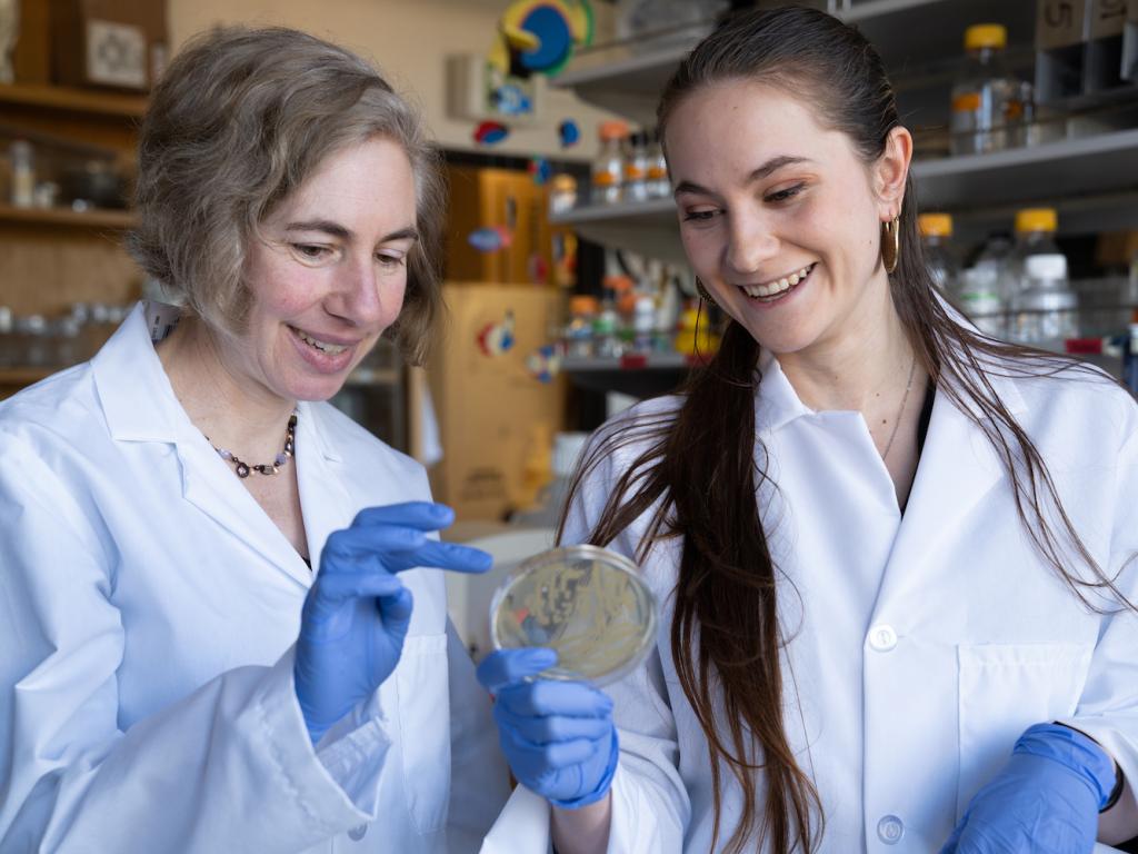 Two female scientists in a lab smiling.