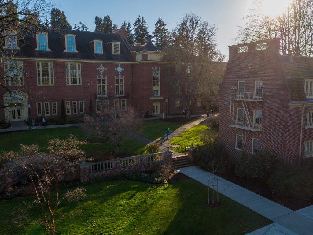 Students walking between red brick campus buildings on a sunny winter day..
