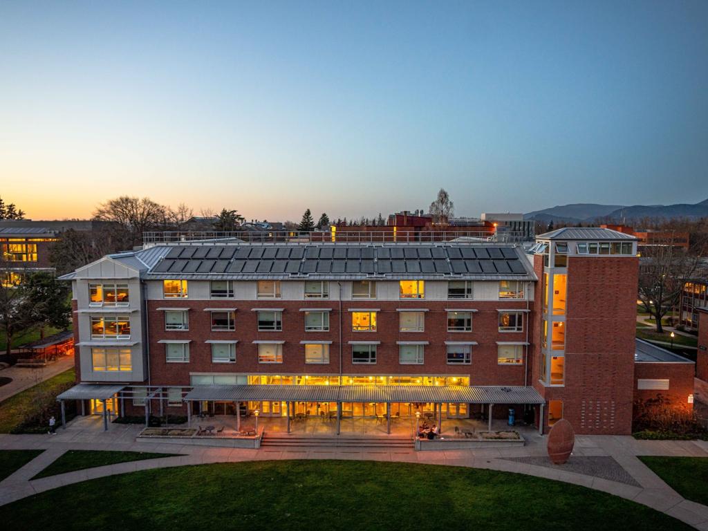 A UO residence hall at dusk with lights on in the windows.