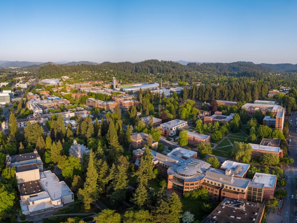 Towering green trees surround the University of Oregon campus buildings.