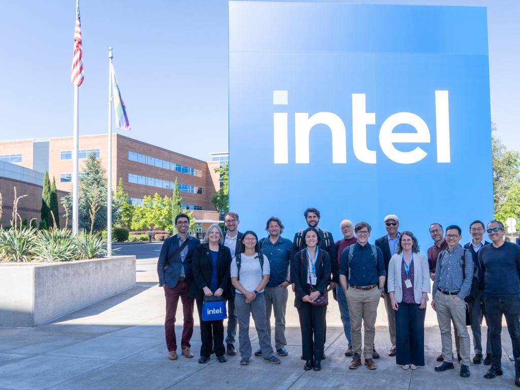 A group of people stand in front of a 15-foot tall blue Intel sign.