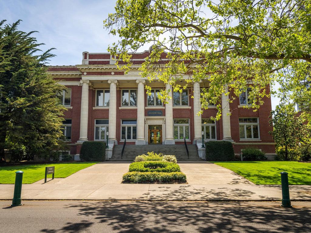 The Johnson Hall administrative building on the UO campus on a spring day as evidenced by new leaves on the trees.