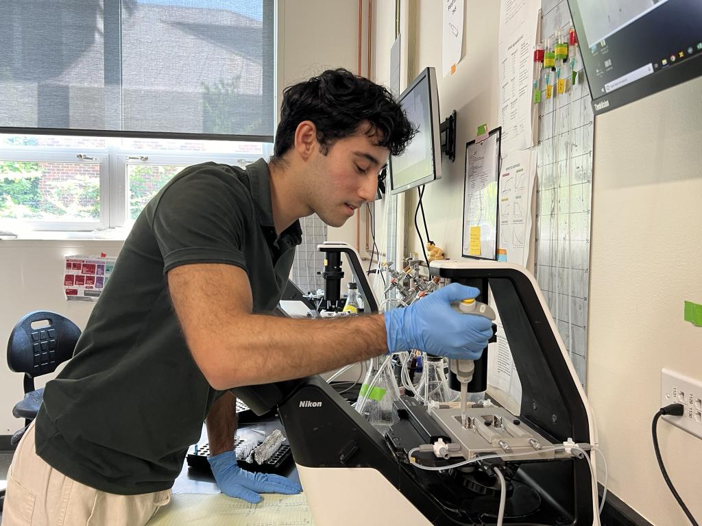 Lazar Isakharov uses a pipette to transfer material in a lab.