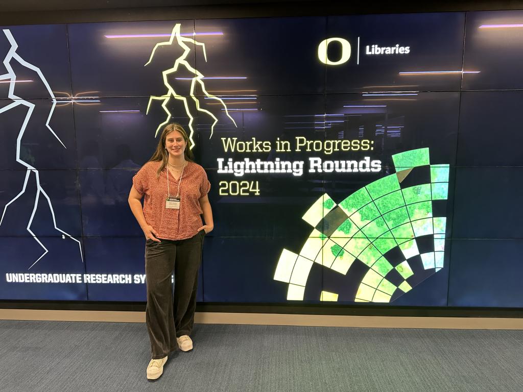 Tapley Sorenson stands in front of a sign at the 2024 Undergraduate Research Symposium.