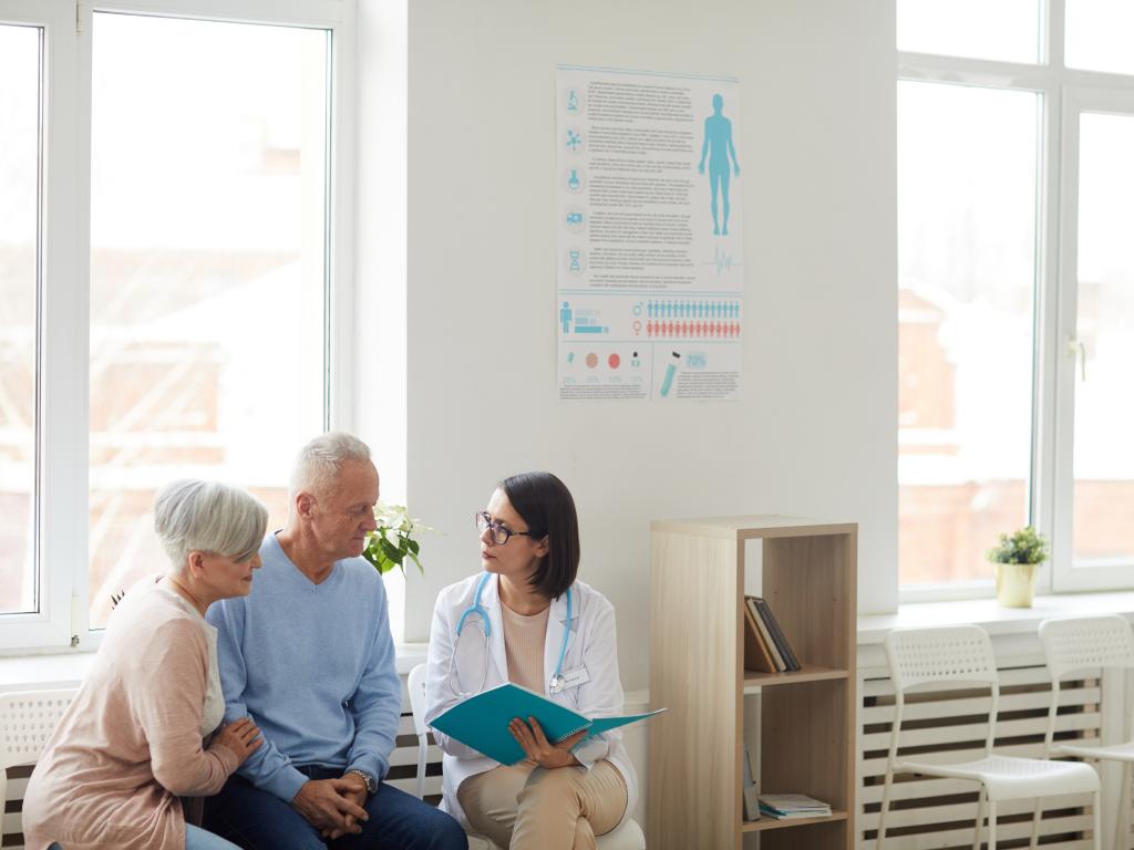 A doctor talking to an older man and woman.