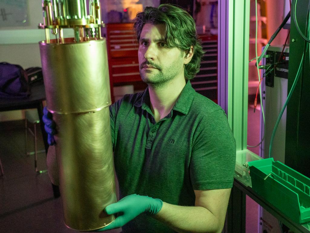 Person holding a copper tube while sliding it onto a cryostat.