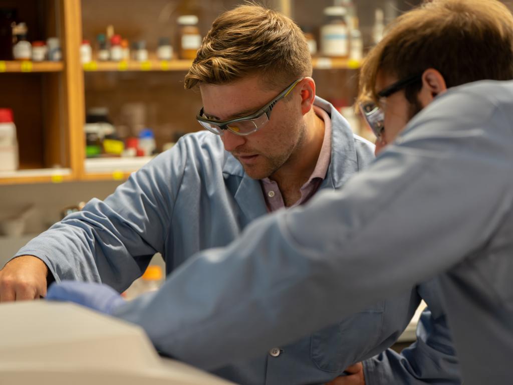 Two researchers in a biochemistry lab look into a machine