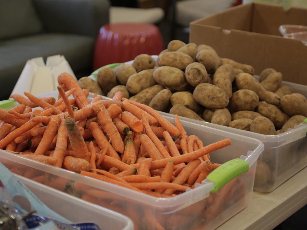 Bins of carrots and potatoes sit on a table.