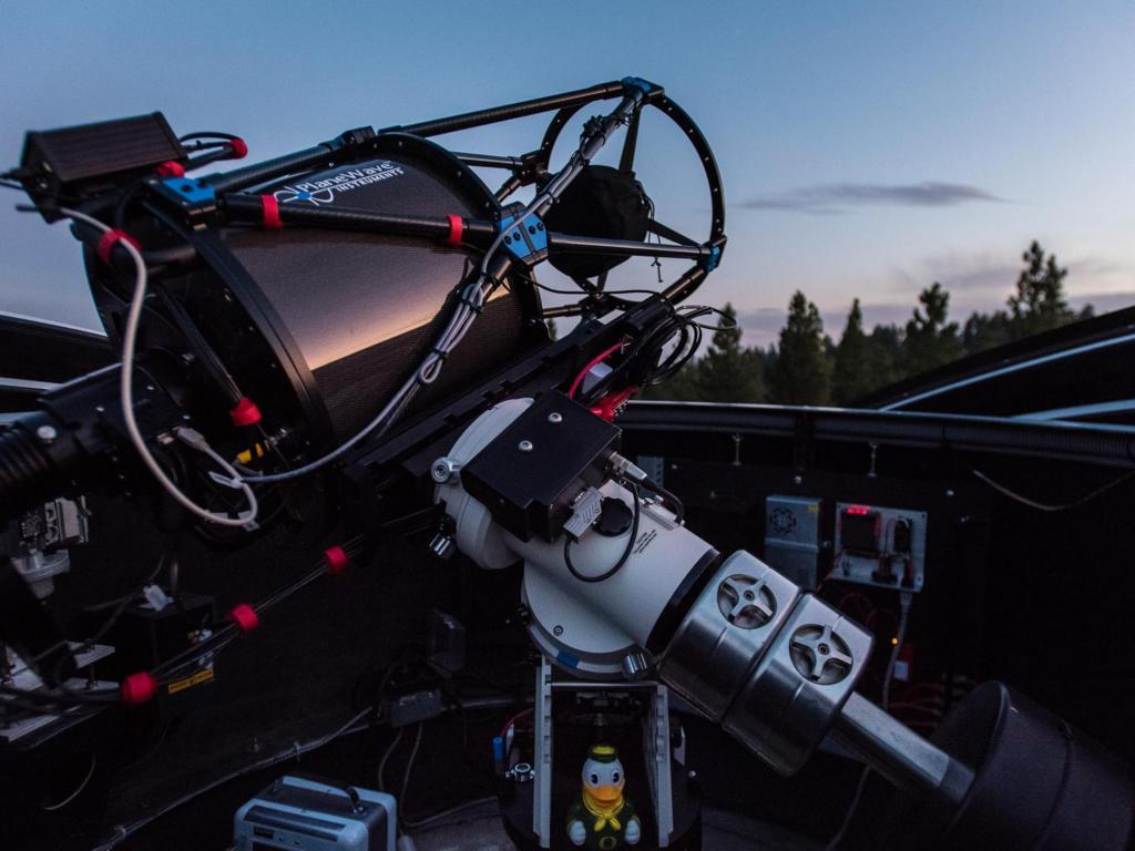 Large, high-tech telescope mounted inside an open observatory dome at dusk