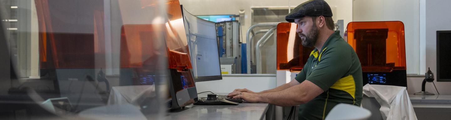 A person sits at a workstation in a brightly lit lab.