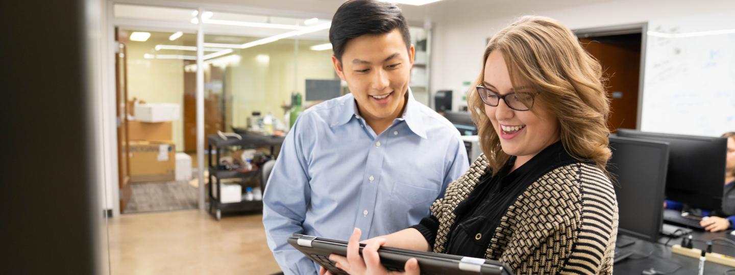 Two people collaborating and looking at a screen.