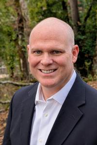 Photo of Elliot Reed smiling with a forest background.