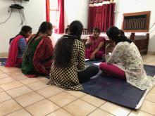 Women gather in a seated circle around a woman who is talking.