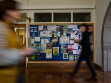 Students walk past a bulletin board in Willamette Hall.