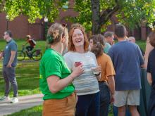 Two people at an outdoor reception smile and laugh.