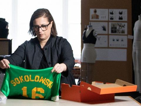 Woman holding a jersey in a clothing design room. 