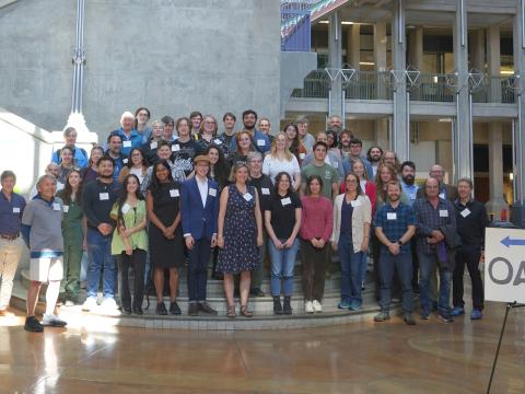 A group of people pose behind a sign reading O A R S. 