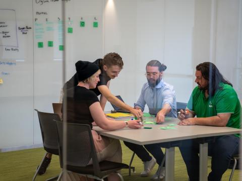 A group of graduate students collaborate around a table piled with sticky notes.