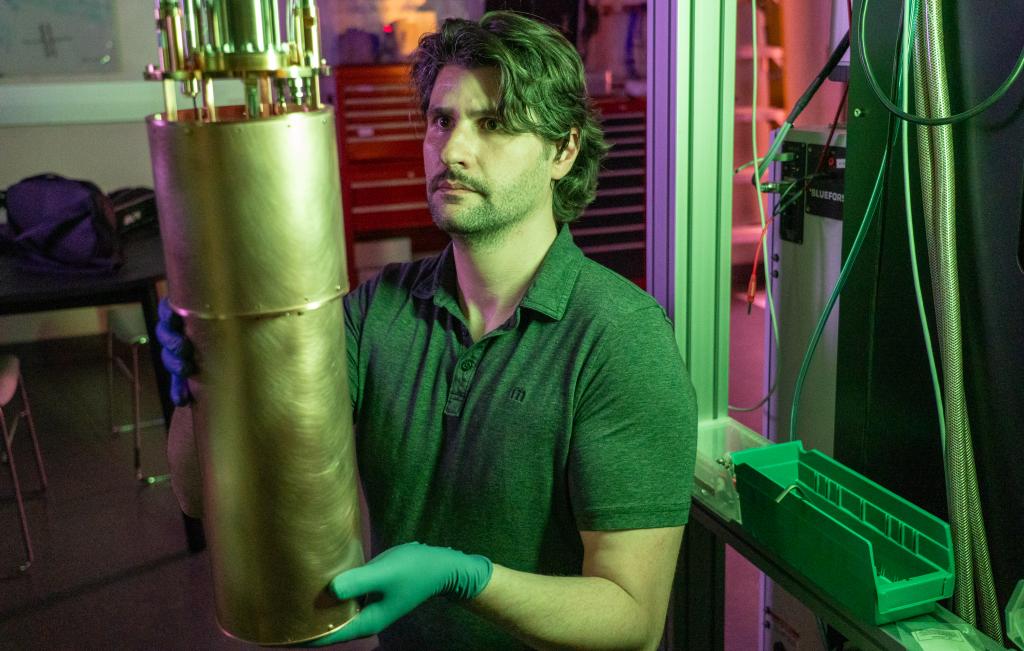 Person holding a copper tube while sliding it onto a cryostat.