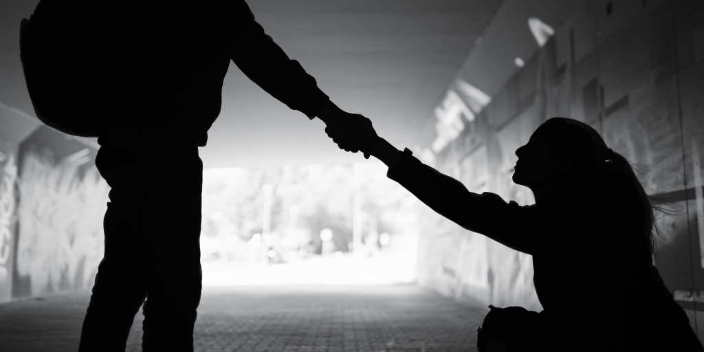 Silhouette of a person extending a hand to help someone up.