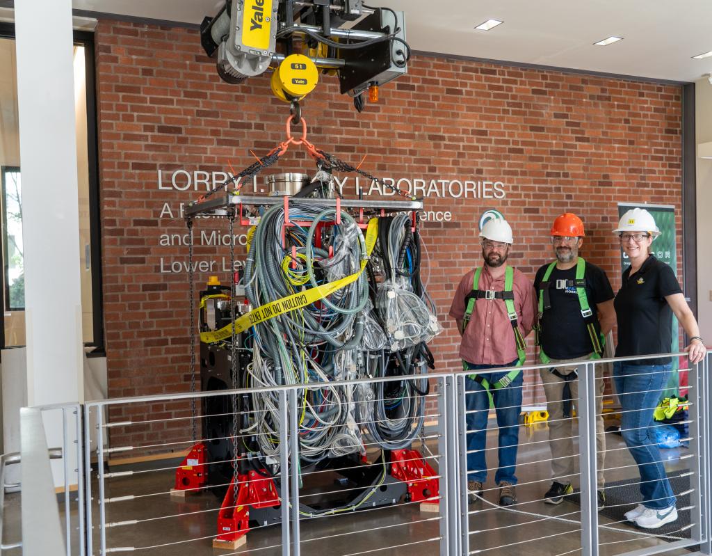 Staff pose with the S/TEM column as it is prepared to be craned down into the CAMCOR space.