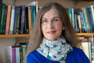 A portrait of Trudy Ann Cameron with books on shelves behind her.