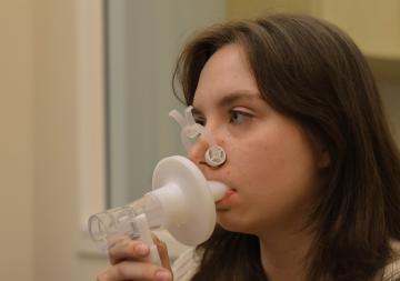 Ava Lindon with an attached nose clip and blowing into the mouthpiece of the spirometer.  