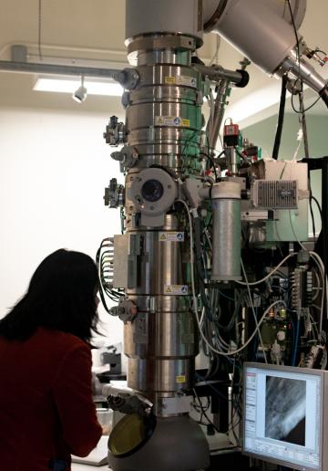 A woman stands in front of machinery in a lab